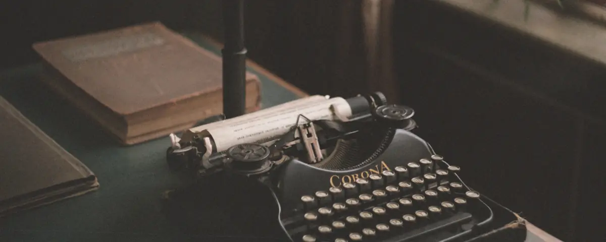 A vintage typewriter with a sheet of paper in it, next to an old book