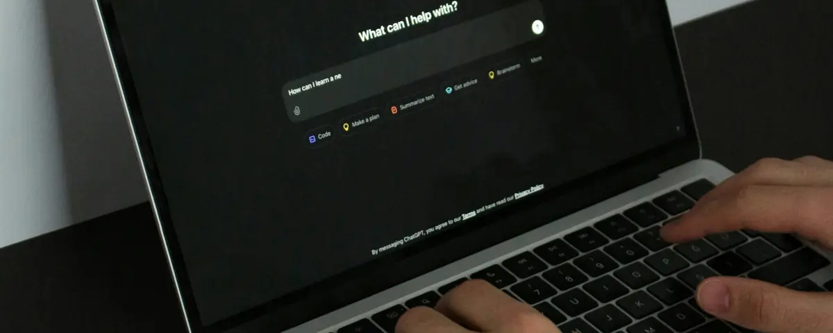 Hands typing on a laptop open on ChatGPT