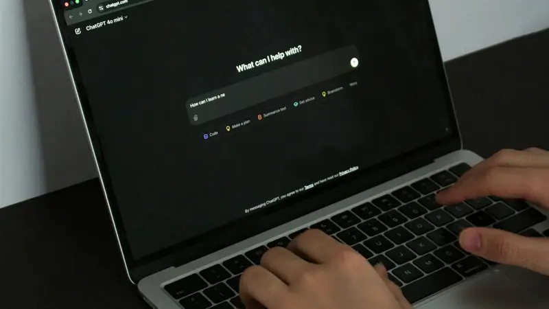 Hands typing on a laptop open on ChatGPT